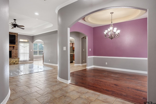 213 Coventry St, Bullard, TX 75757 - empty room with a tray ceiling, ceiling fan, a brick fireplace, stone tile floors, and a chandelier