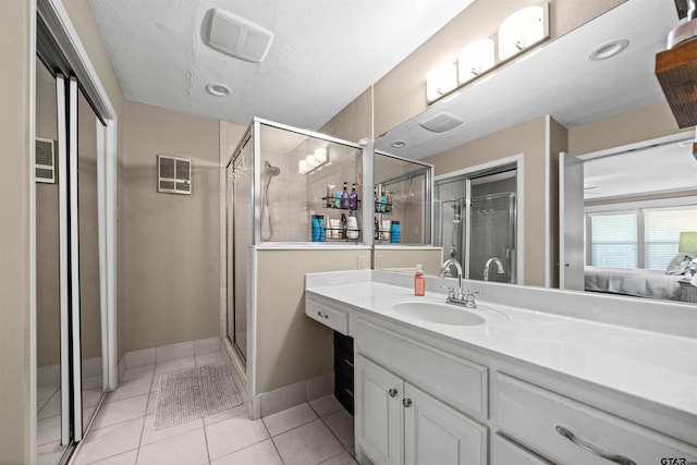 bathroom featuring vanity, a textured ceiling, tile patterned floors, and a shower with door