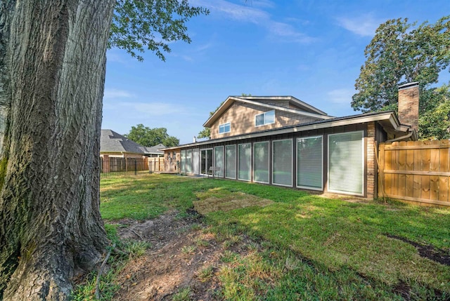 back of house with a lawn and a sunroom