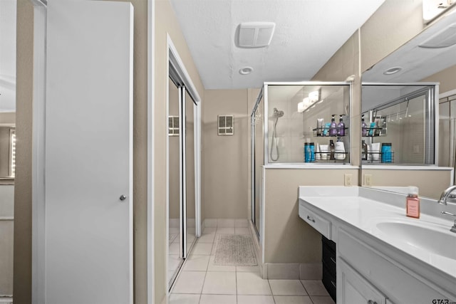 bathroom with an enclosed shower, vanity, a textured ceiling, and tile patterned floors