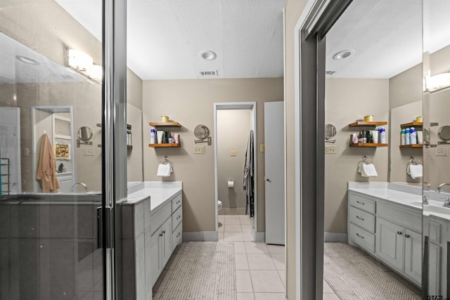 bathroom featuring walk in shower, a textured ceiling, vanity, tile patterned floors, and toilet