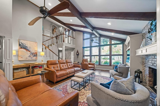 living room featuring high vaulted ceiling, hardwood / wood-style floors, a brick fireplace, beamed ceiling, and ceiling fan