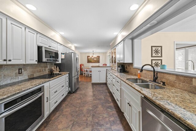 kitchen with stainless steel appliances, white cabinets, decorative backsplash, sink, and light stone countertops