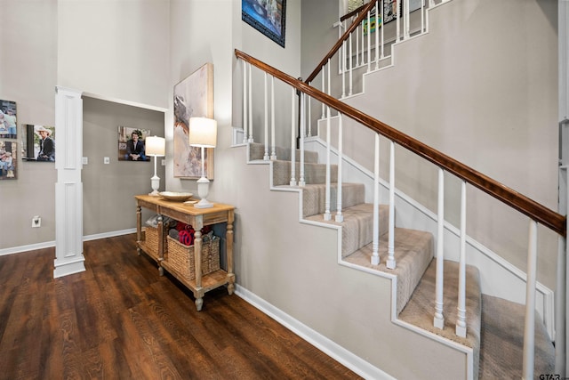 stairs featuring a high ceiling, wood-type flooring, and ornate columns