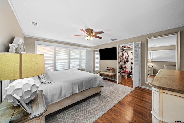 bedroom with a closet, a spacious closet, ornamental molding, dark wood-type flooring, and ceiling fan