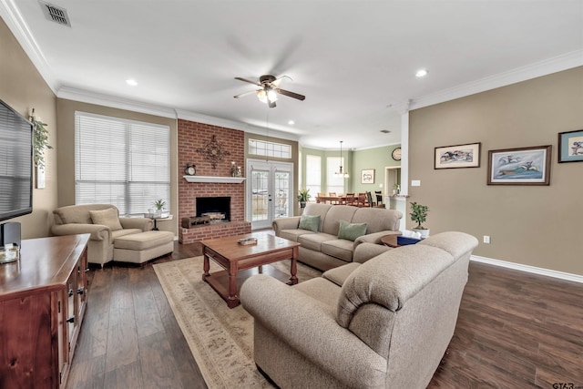 living room featuring ceiling fan, french doors, a brick fireplace, dark hardwood / wood-style flooring, and crown molding