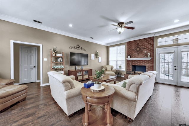 living room with french doors, a brick fireplace, ceiling fan, crown molding, and dark wood-type flooring