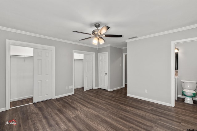 unfurnished bedroom featuring multiple closets, crown molding, and dark wood-type flooring