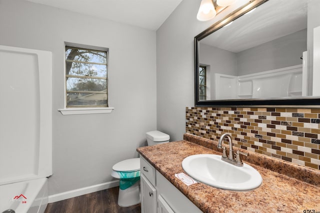 bathroom featuring tasteful backsplash, vanity, wood-type flooring, and toilet