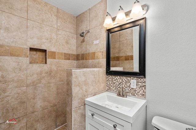 bathroom featuring vanity, tiled shower, backsplash, and toilet