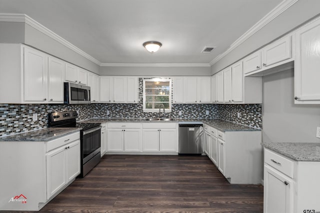 kitchen featuring sink, white cabinetry, appliances with stainless steel finishes, dark hardwood / wood-style flooring, and dark stone counters