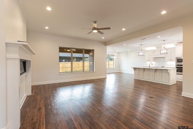 unfurnished living room with ceiling fan, ornamental molding, dark hardwood / wood-style floors, and sink