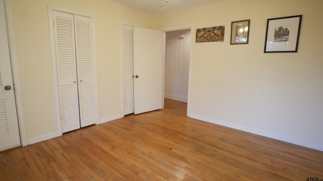 unfurnished bedroom featuring light hardwood / wood-style flooring and multiple closets