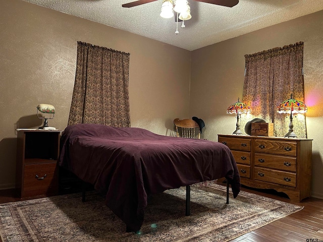 bedroom with ceiling fan, wood-type flooring, and a textured ceiling