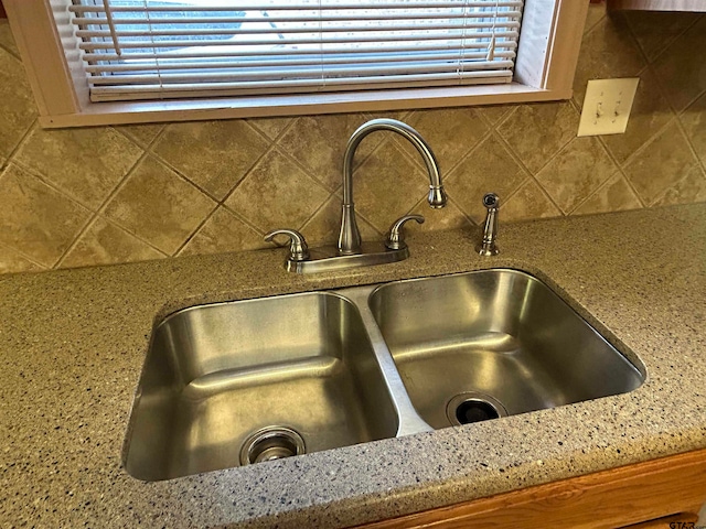 interior details featuring tasteful backsplash, light stone countertops, and sink