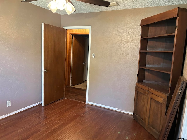 unfurnished bedroom featuring ceiling fan, a textured ceiling, and dark hardwood / wood-style floors