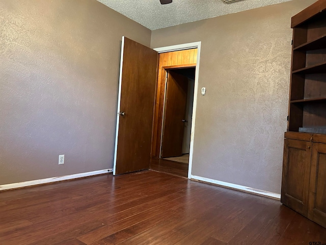 unfurnished room with dark wood-type flooring and a textured ceiling