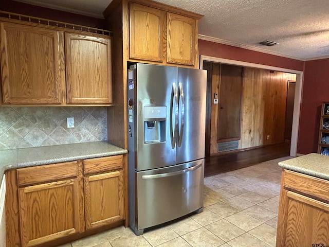 kitchen featuring a textured ceiling, tasteful backsplash, stainless steel fridge with ice dispenser, ornamental molding, and light tile patterned flooring