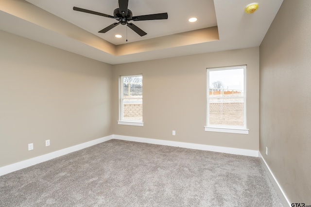 carpeted spare room featuring ceiling fan and a tray ceiling