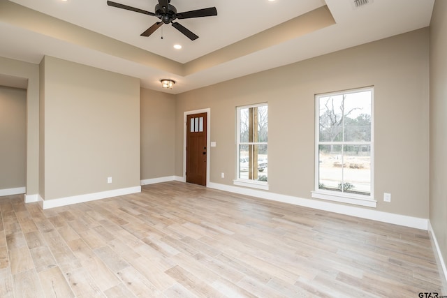 foyer entrance featuring a raised ceiling, ceiling fan, and light wood-type flooring