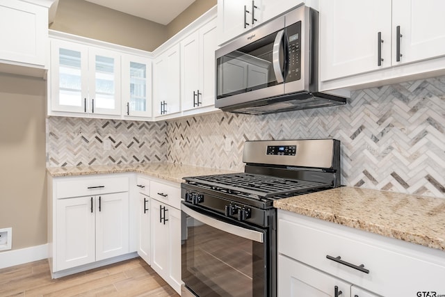 kitchen with light stone counters, stainless steel appliances, and white cabinets