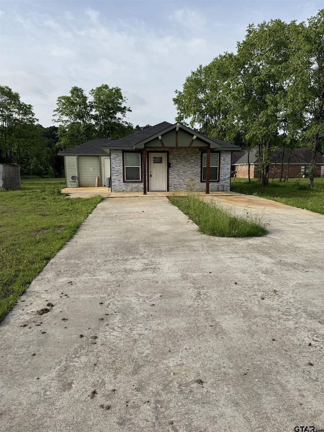 view of front of home with a front lawn, concrete driveway, and stone siding