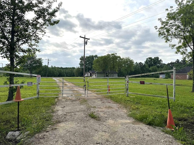 view of street featuring driveway, a gate, a rural view, and a gated entry