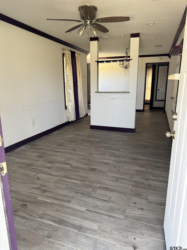 empty room with baseboards, wood finished floors, ceiling fan, and crown molding