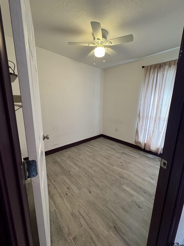 spare room with a ceiling fan, a textured ceiling, wood finished floors, and baseboards
