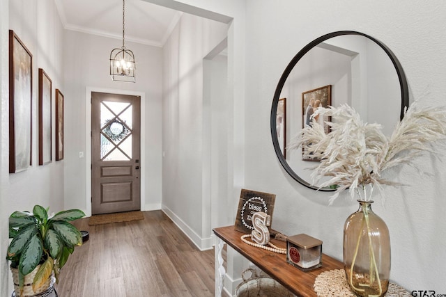 foyer featuring light hardwood / wood-style flooring, a chandelier, and crown molding