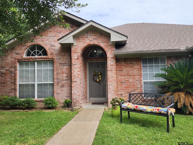 670 Frederick Cir, Flint, TX 75762 - view of exterior entry featuring brick siding, a shingled roof, and a lawn
