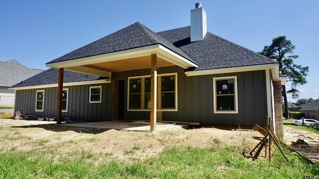 24062 Sun Ridge Rd, Lindale, TX 75771 - rear view of house featuring roof with shingles, board and batten siding, a chimney, and a patio