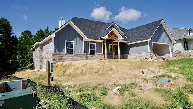 24062 Sun Ridge Rd, Lindale, TX 75771 - view of front of home with board and batten siding, a chimney, brick siding, and a shingled roof