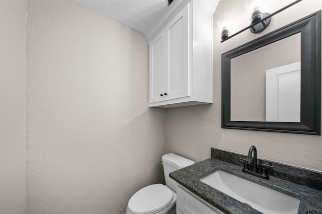 bathroom featuring toilet, vanity, and a textured ceiling