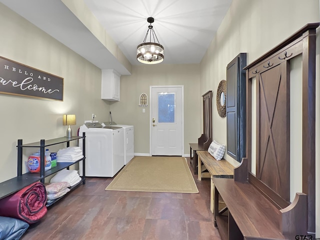 washroom featuring baseboards, washing machine and clothes dryer, cabinet space, and a notable chandelier