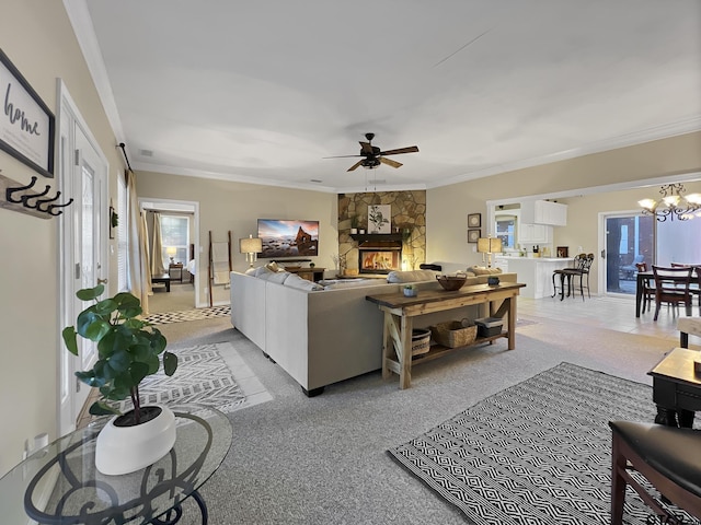 living room with ceiling fan with notable chandelier, crown molding, and a stone fireplace