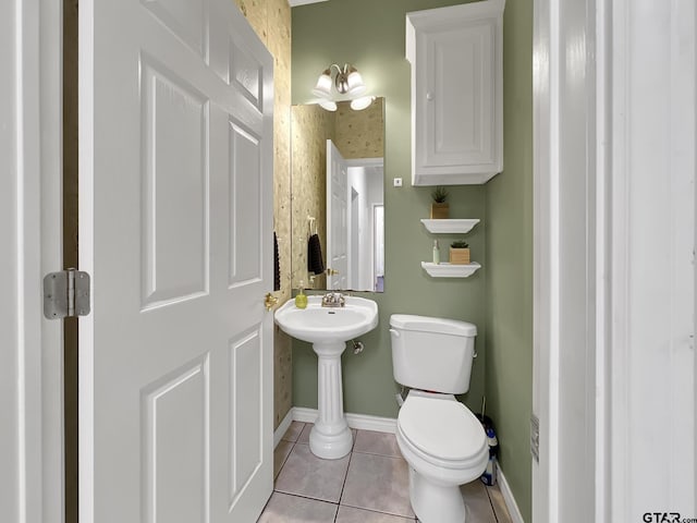 bathroom featuring toilet, tile patterned flooring, baseboards, and a sink