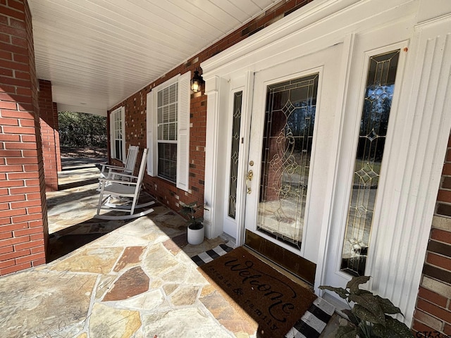 property entrance with covered porch and brick siding