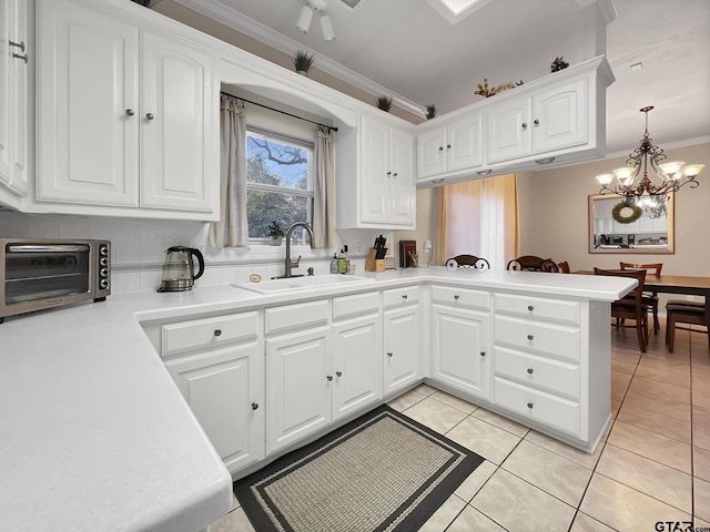 kitchen featuring light tile patterned floors, a toaster, white cabinets, crown molding, and a sink