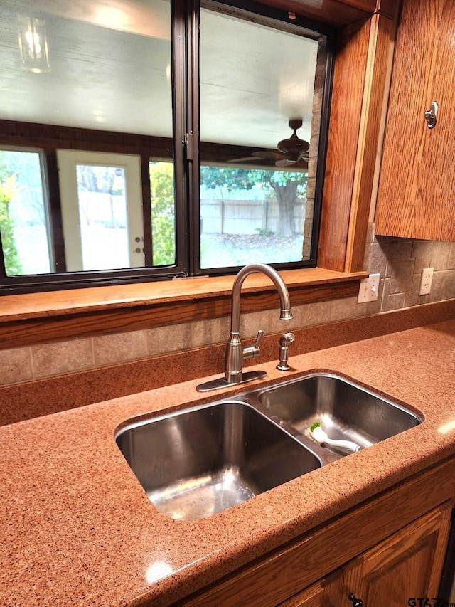 kitchen with backsplash, light stone countertops, and sink