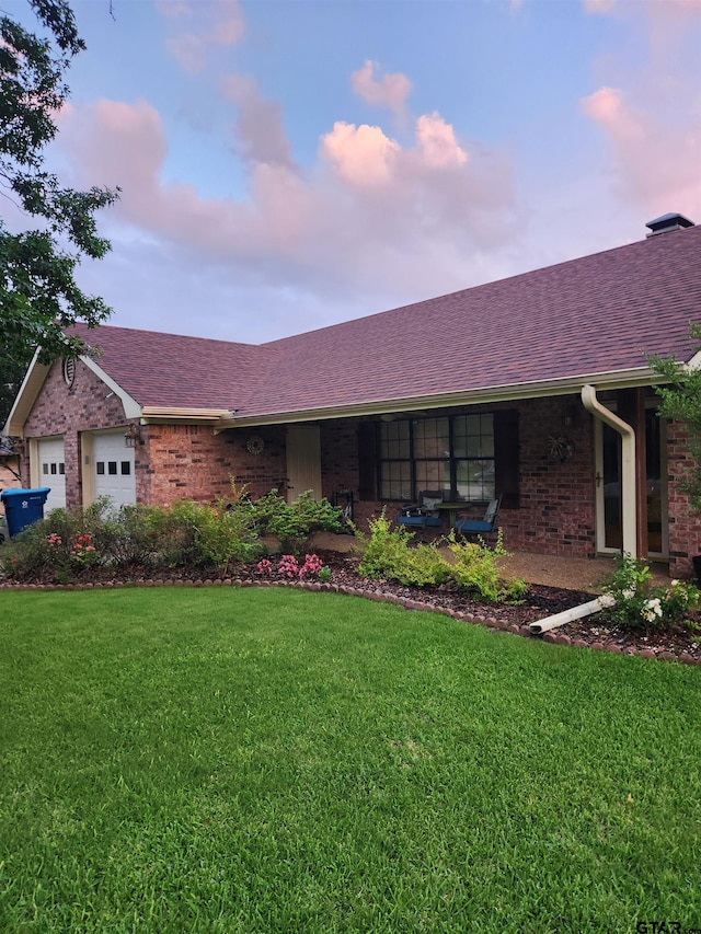 ranch-style house featuring a garage and a yard