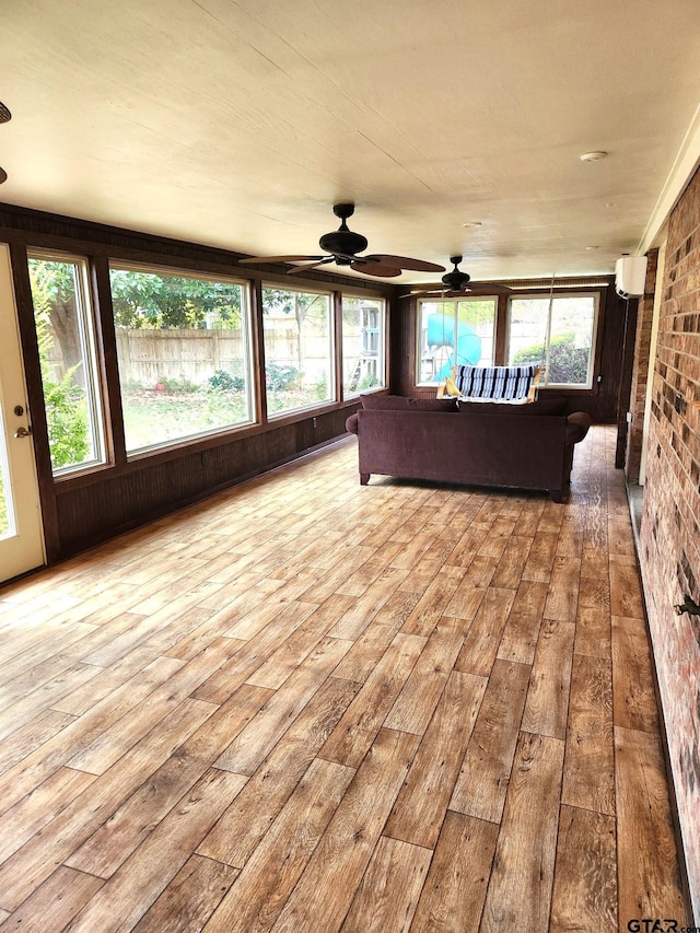 unfurnished sunroom featuring a wall mounted air conditioner and ceiling fan