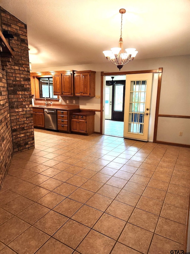 kitchen featuring stainless steel dishwasher, brick wall, light tile patterned floors, an inviting chandelier, and hanging light fixtures