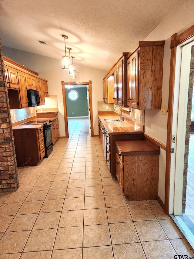 kitchen with a textured ceiling, sink, black appliances, light tile patterned floors, and pendant lighting