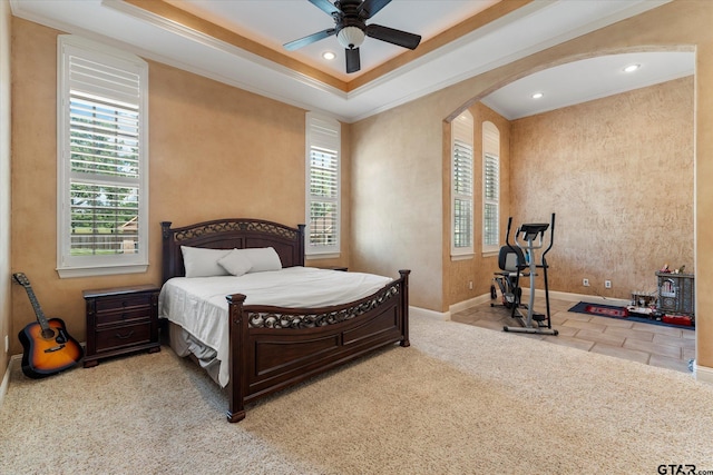 bedroom featuring light colored carpet, ceiling fan, crown molding, and a tray ceiling