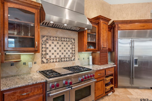 kitchen with tasteful backsplash, extractor fan, light stone countertops, and high end appliances