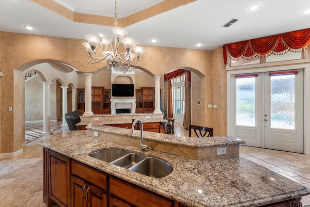 kitchen with pendant lighting, sink, ornate columns, and light stone countertops