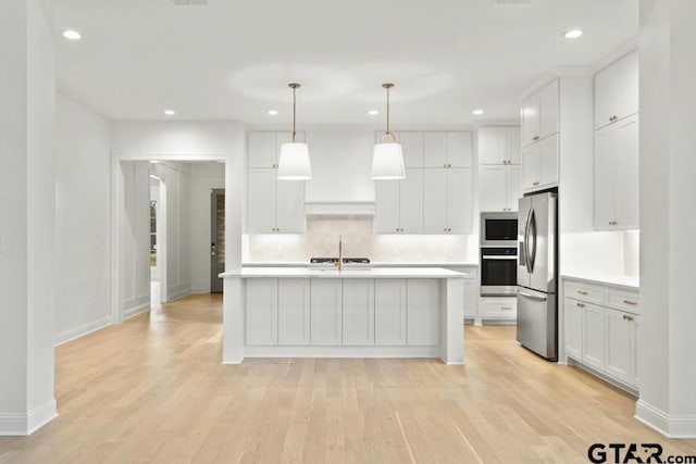 kitchen with a sink, light countertops, light wood-type flooring, and stainless steel appliances