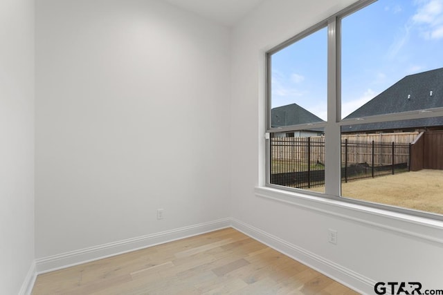 spare room with baseboards and wood finished floors