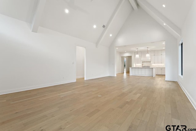 unfurnished living room featuring baseboards, light wood finished floors, high vaulted ceiling, recessed lighting, and beamed ceiling